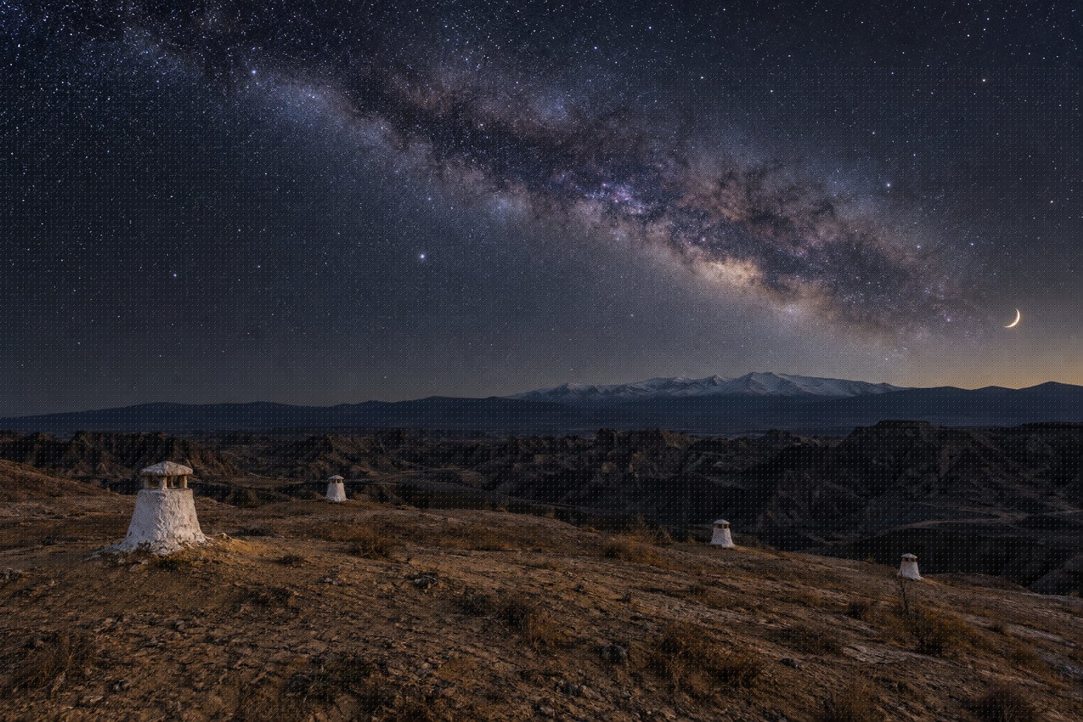 Escapada rural a Guadix: cine, cuevas y la lección de María Galiana 3 Chimeneas blancas asomando de una ladera de arcilla bajo un cielo nocturno lleno de estrellas en el altiplano de Guadix